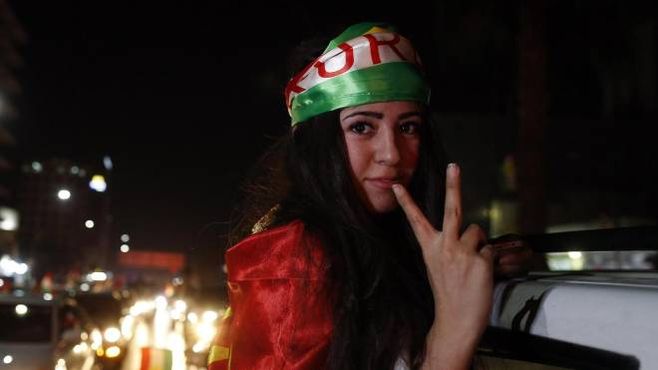 Una giovane curda festeggia in strada avvolta