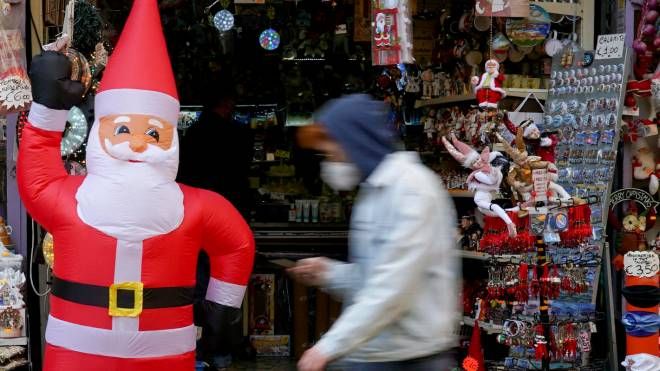 Un uomo con la mascherina passa accanto a un pupazzo di Babbo Natale